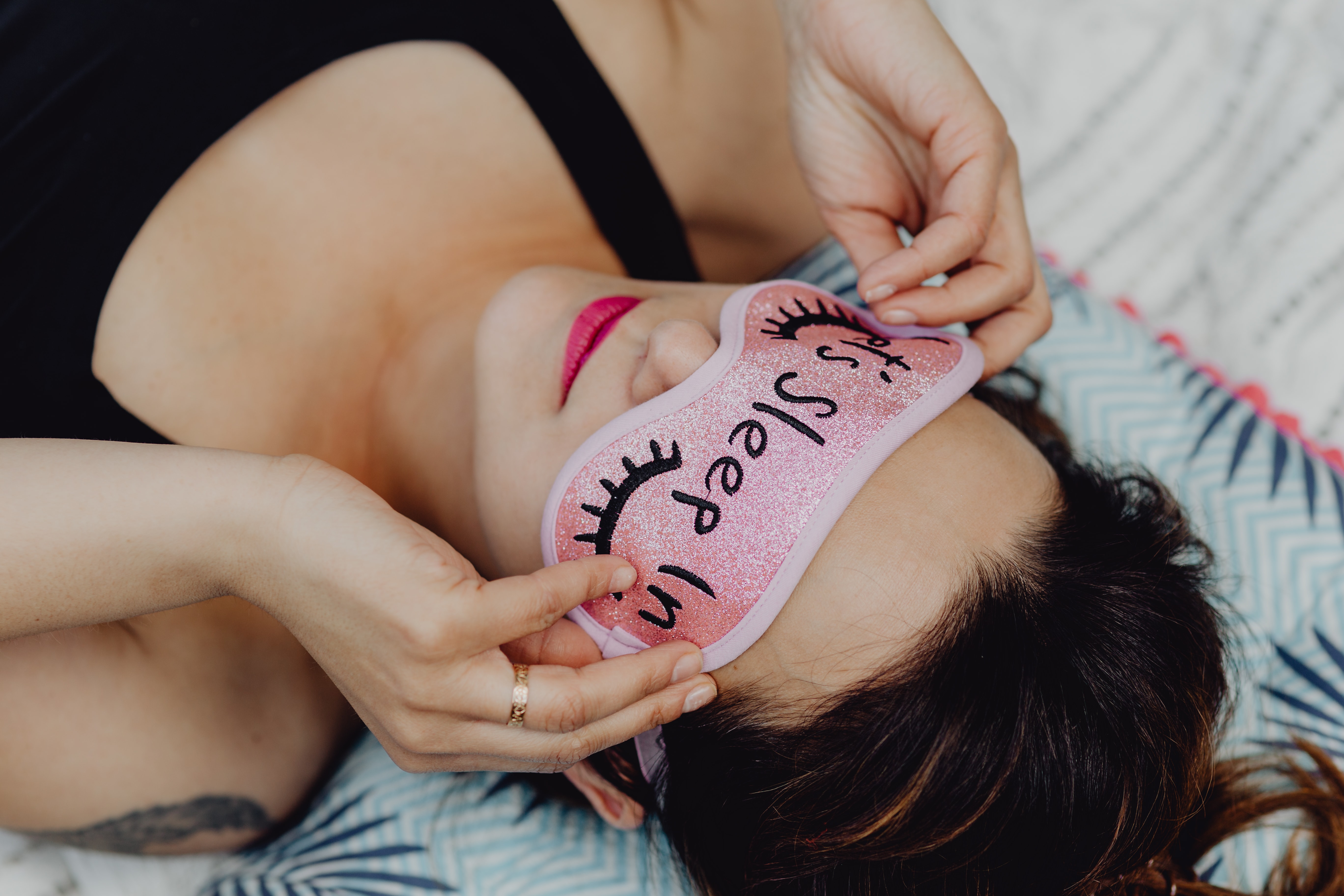 kaboompics_Joyful girl relaxing in bedroom - top view of brunette women in pink sleeping mask